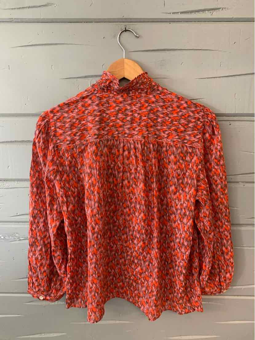 Long-sleeve blouse in red and black knit pattern with ruffled high neckline and hemmed cuffs.