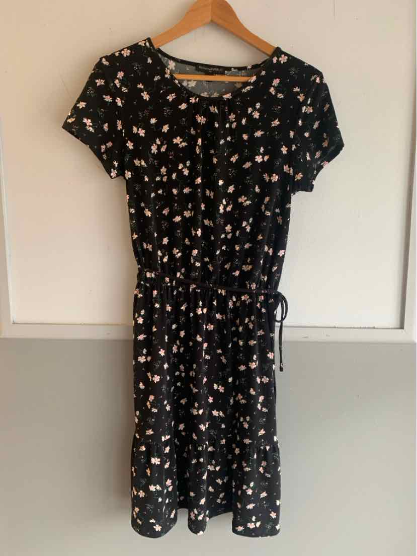 Black short-sleeve dress with small pink and white floral print and cinched waist tie.