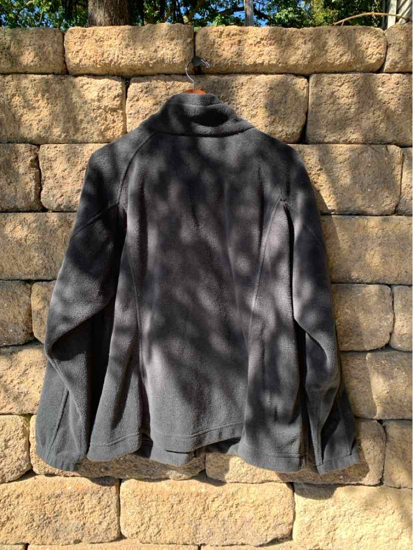 Black Columbia fleece jacket in size 2X with full sleeves and stand collar hanging outdoors.