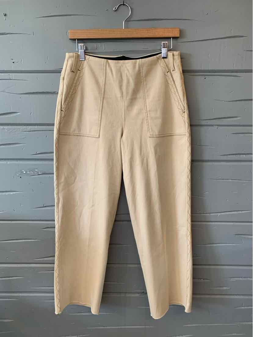 Tan straight-leg pants with large front patch pockets and a high waist, hanging on a wooden hanger.