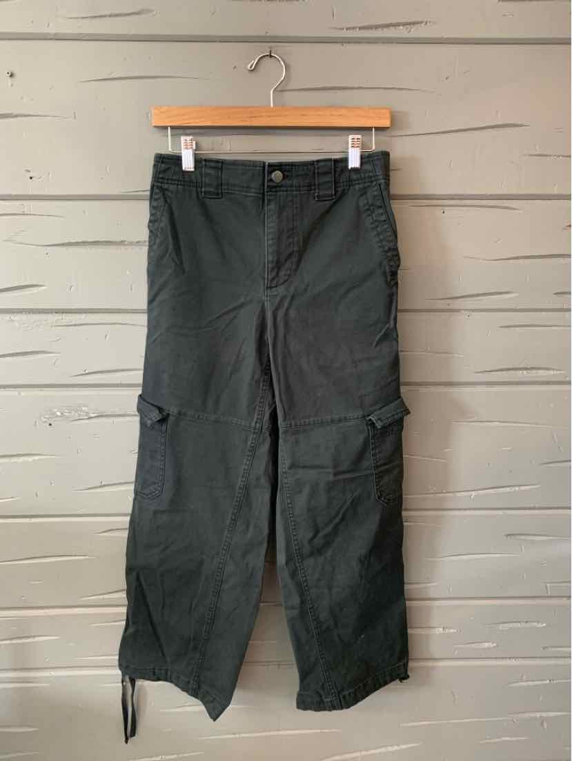 Black cargo pants in small size with multiple pockets and adjustable ankle ties, hanging on wooden hanger.