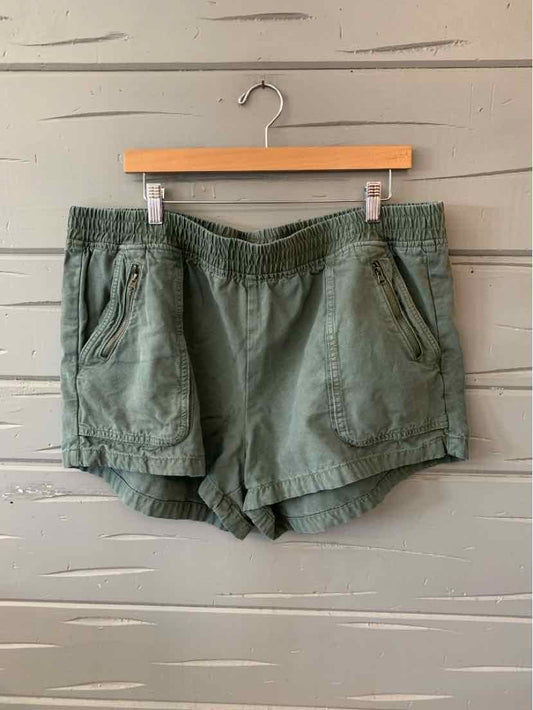 Olive green casual shorts with elastic waistband and front pockets, hanging on wooden hanger.