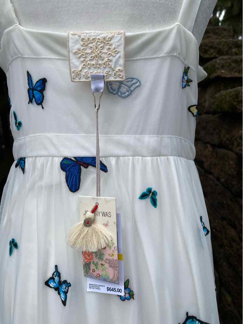 White dress with blue and teal butterfly embroidery, sleeveless with fitted waist.