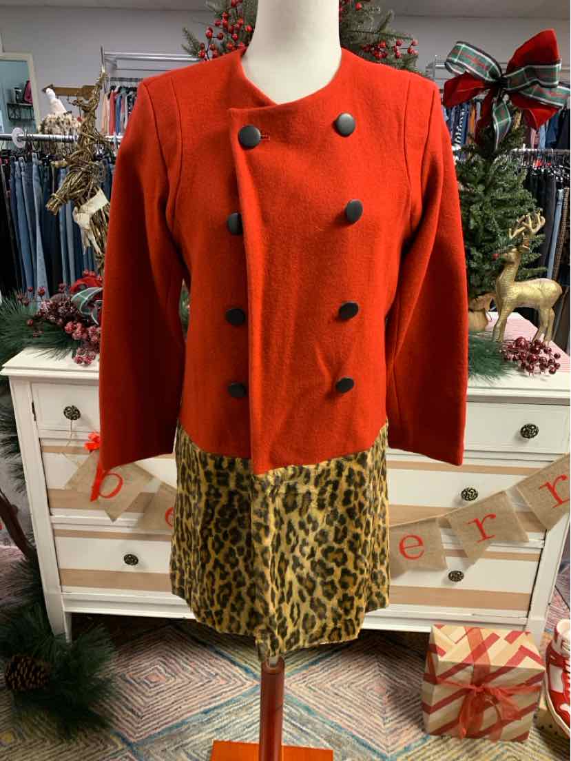 Orange double-breasted wool jacket with black buttons on mannequin over leopard print skirt.
