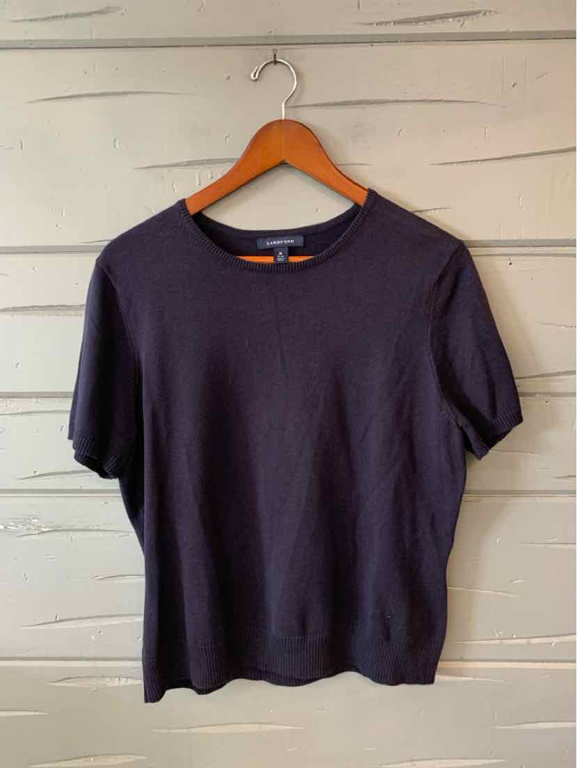 Navy blue short-sleeve knit top with crew neckline and relaxed fit on wooden hanger.