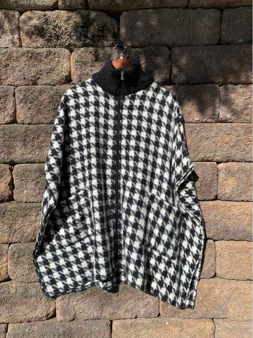 Black and white houndstooth poncho-style coat with a high collar and wide, draped sleeves.