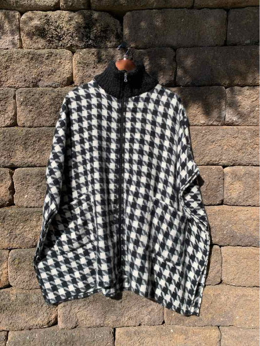 Black and white houndstooth poncho-style coat with a high collar and wide, draped sleeves.