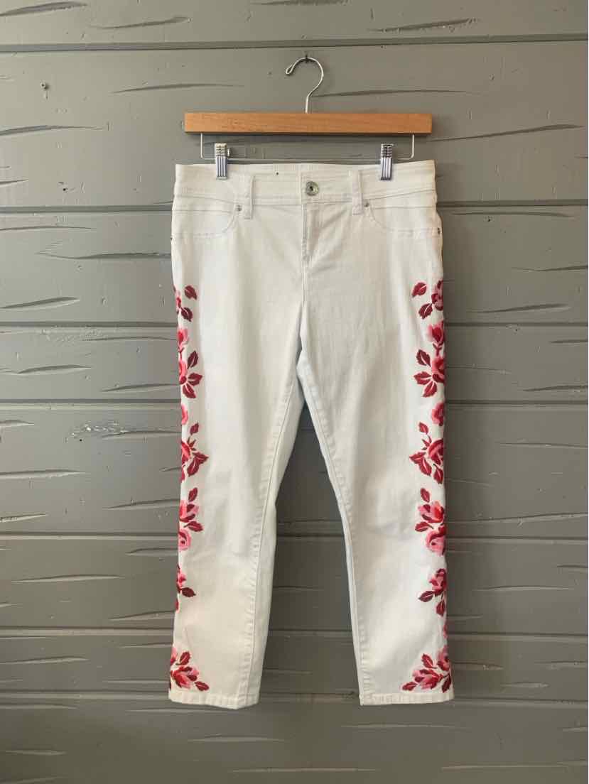 White denim pants with red floral embroidery along the outer sides and cropped length.