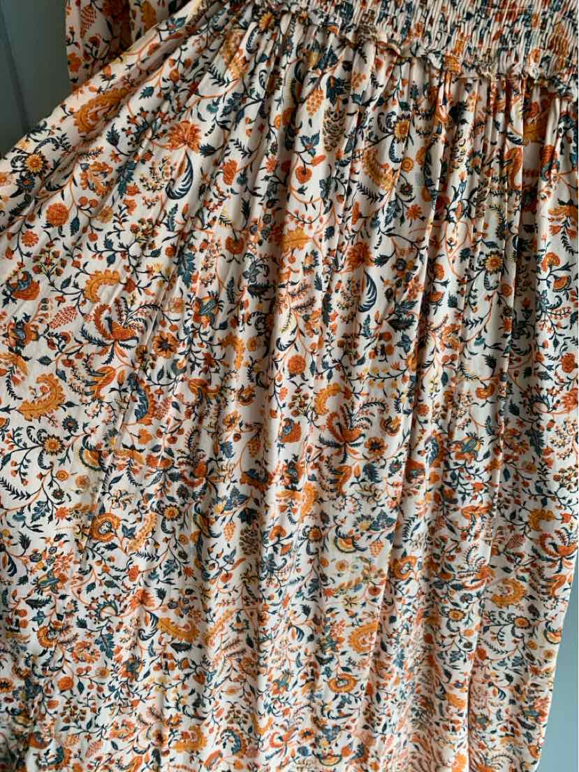 Lightweight orange and white floral print fabric with gathered elastic waistband on dress.