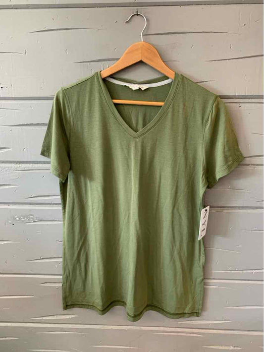 Olive green women's V-neck short sleeve T-shirt hanging on wooden hanger against gray wooden wall.