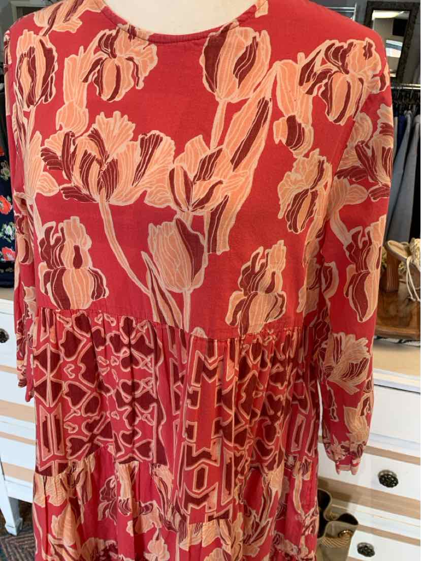 Red long-sleeve dress with abstract floral and geometric pink patterns, round neckline, and tiered skirt.