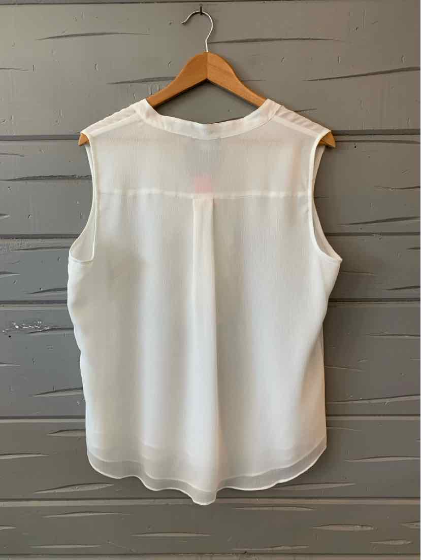 White sleeveless blouse with rounded hem on wooden hanger against gray wall.