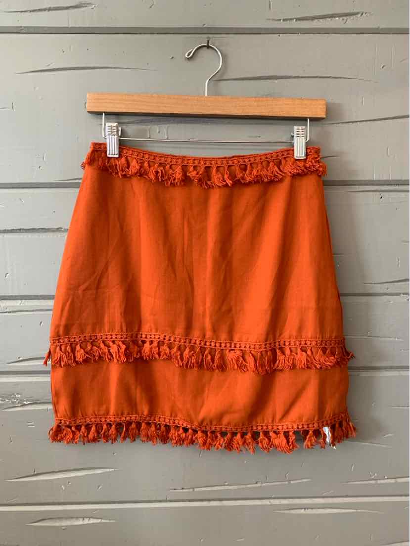 Rust orange mini skirt with ruffled elastic waistband and tiers of ruffle trim.