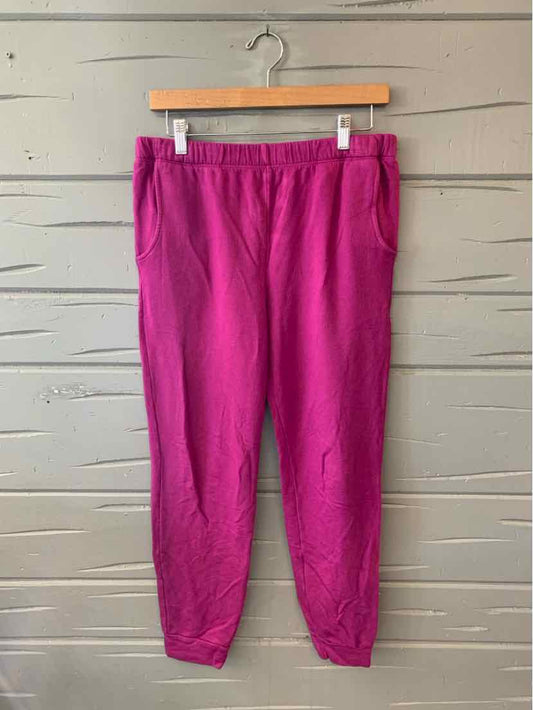 Bright pink casual jogger pants with elastic waistband and side pockets on wooden hanger.