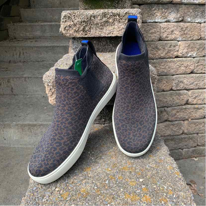 Slip-on sneakers in dark brown and black cheetah print fabric with white rubber soles and navy blue interior lining.