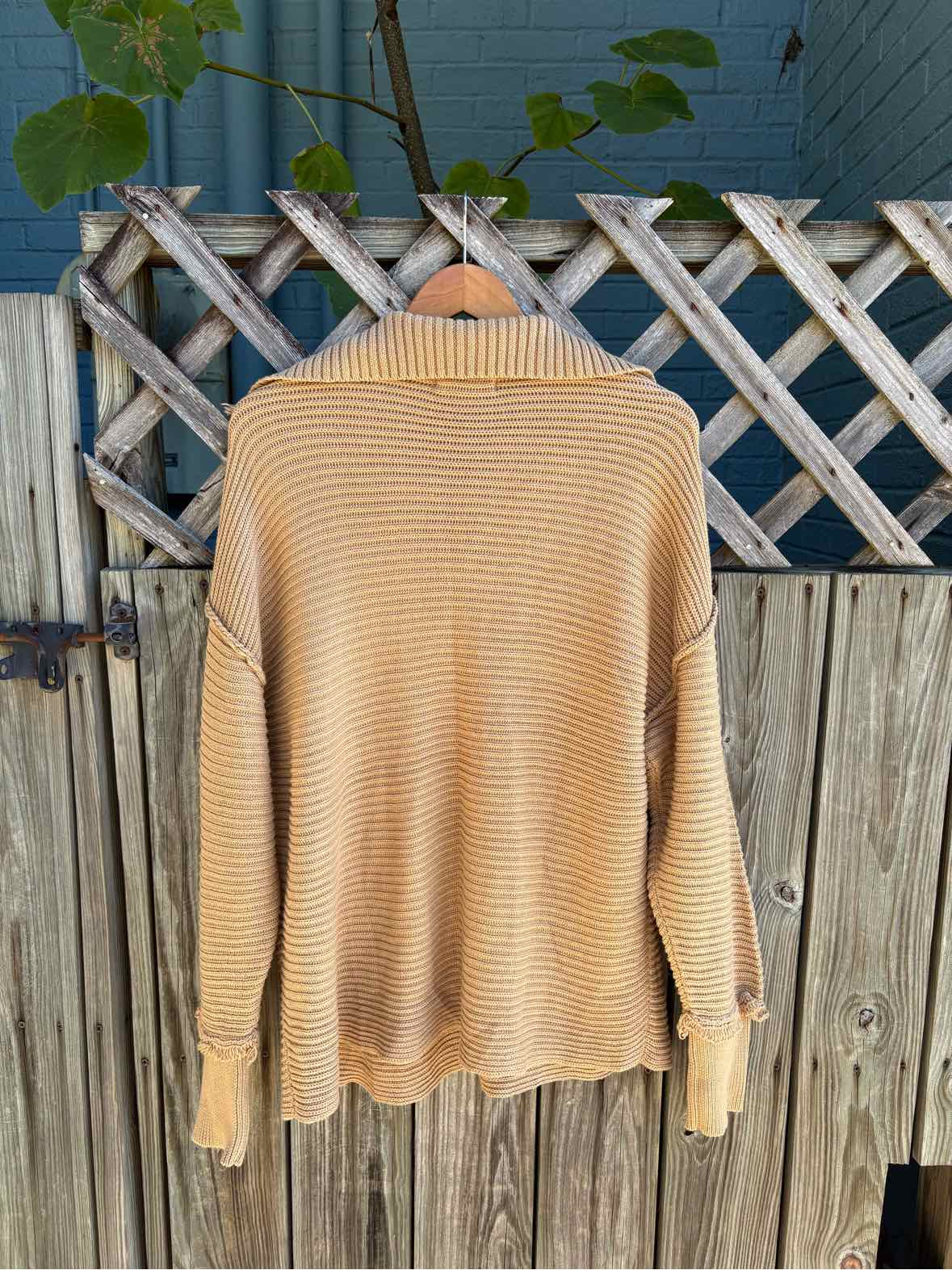 Tan ribbed knit sweater with a high crew neckline, long sleeves, and a relaxed fit.
