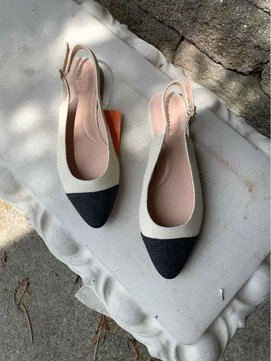 Two-tone tan and black pointed-toe slingback flats with a low heel and leather finish.
