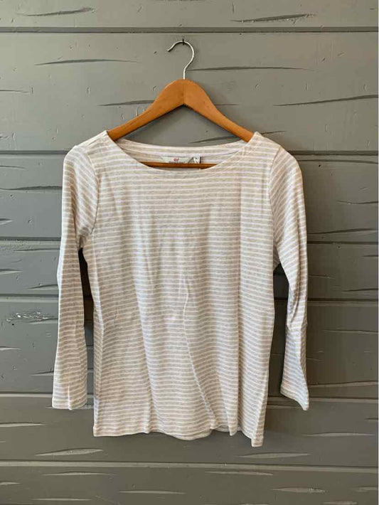 Long-sleeve tan and white striped crew neck shirt on wooden hanger against gray wood wall.