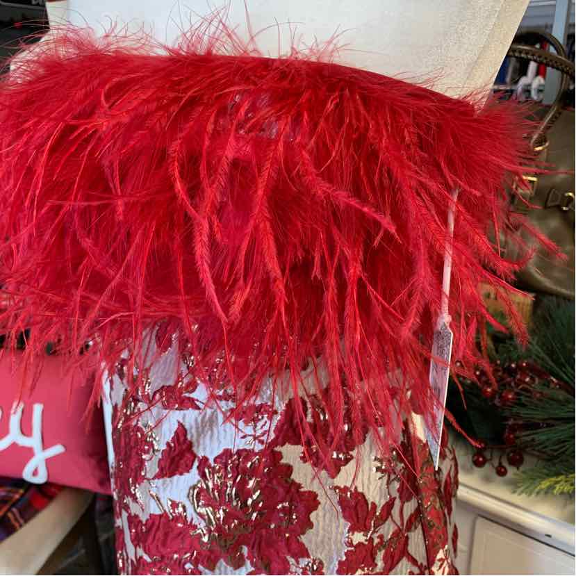 Red feathered decorative pillow on floral jacquard fabric background.