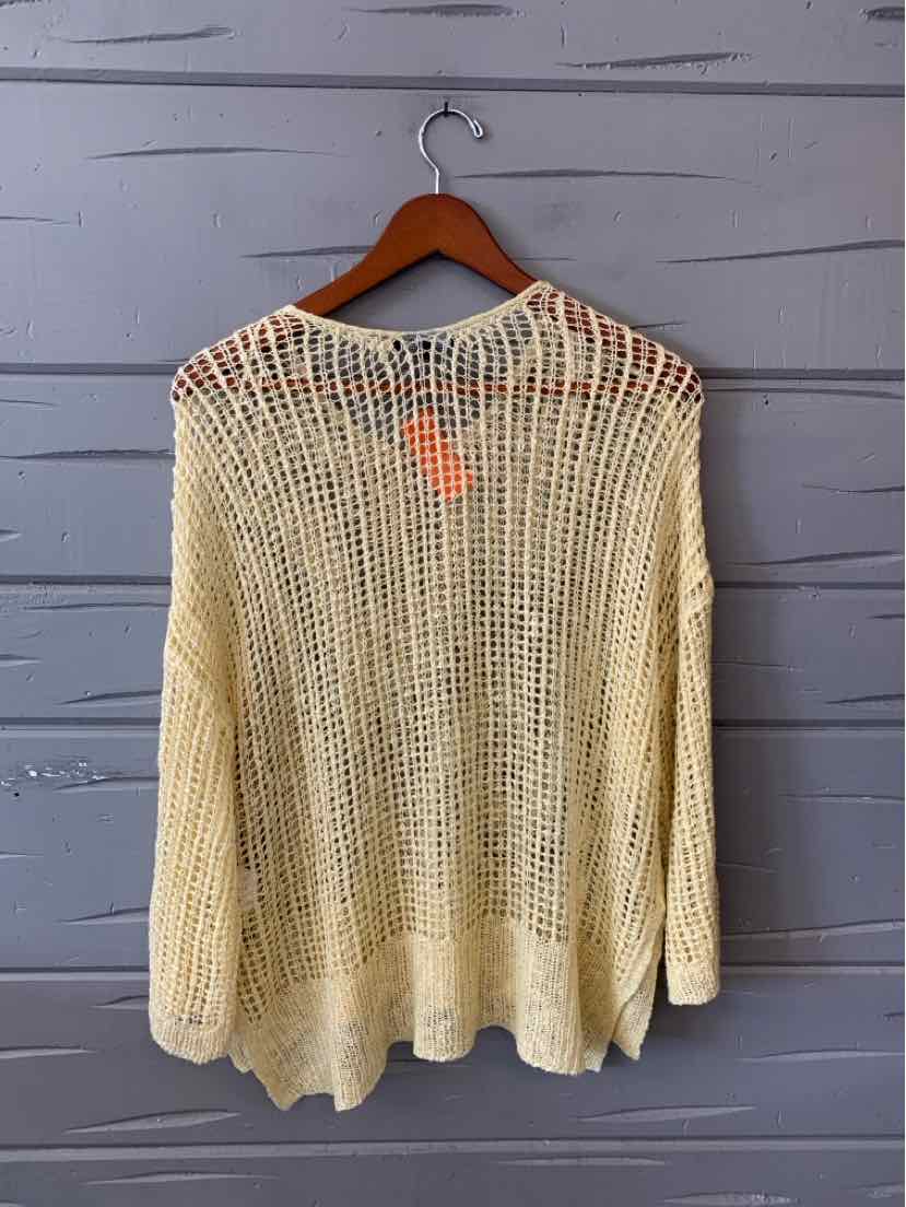 Light yellow long-sleeve open-knit sweater with relaxed fit on wooden hanger.