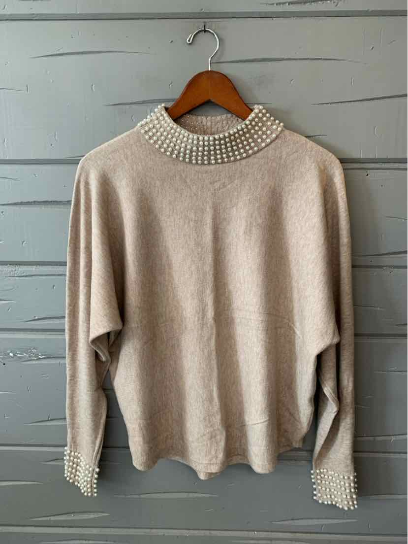 Beige knit sweater with a loose draped fit, high embellished neckline, and matching cuffs.