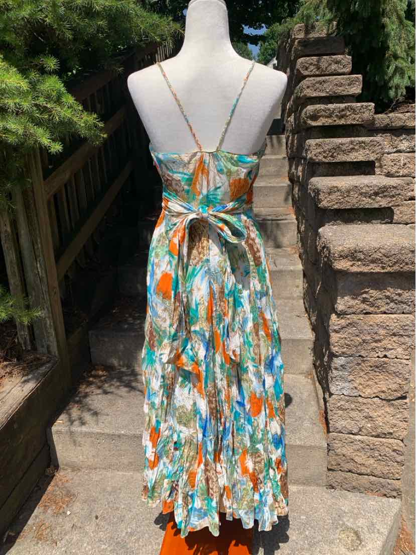 Sleeveless midi dress with thin straps, multicolor floral pattern, and a tied waist sash on back.