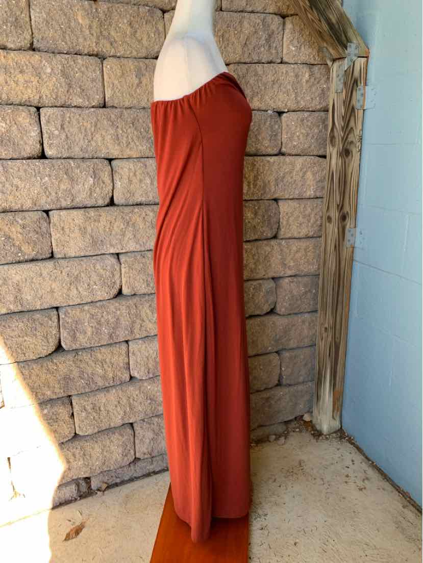Rust-red Free People maxi dress with a draped, off-the-shoulder neckline and flowing skirt on a mannequin.