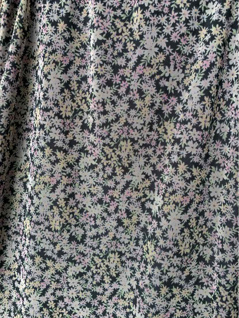 Black fabric with dense small pink and white floral print on a soft, lightweight material.