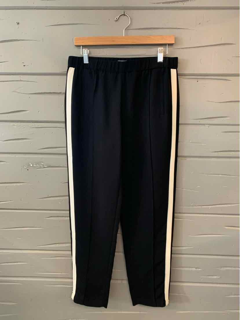 Black slim-fit pants with white side stripes and elastic waistband on a wooden hanger.