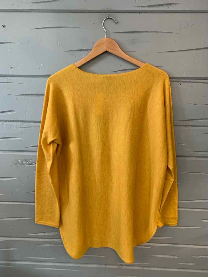 Mustard yellow cashmere long-sleeve sweater with a relaxed fit and boat neckline hanging on wooden hanger.