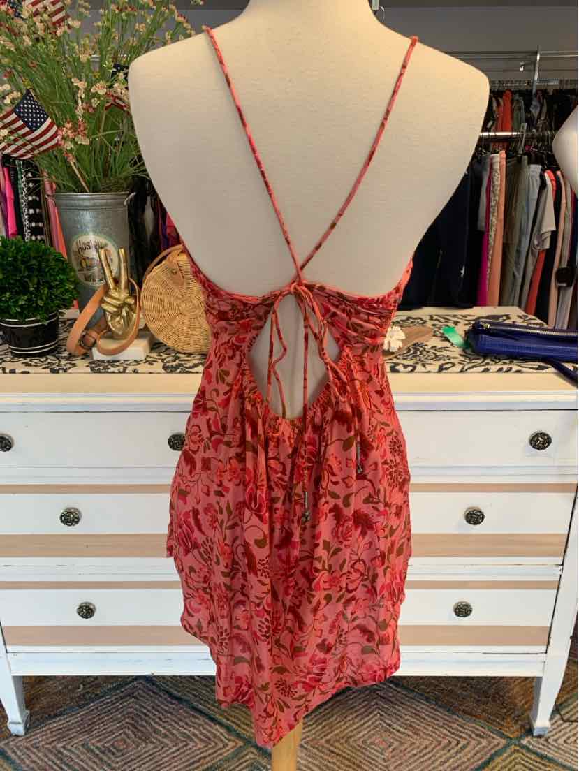 Pink floral sleeveless dress with crisscross back straps and open back detail.