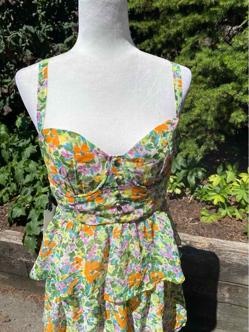 Floral sleeveless dress with green, orange, and purple pattern, fitted bodice, and peplum waist detail.