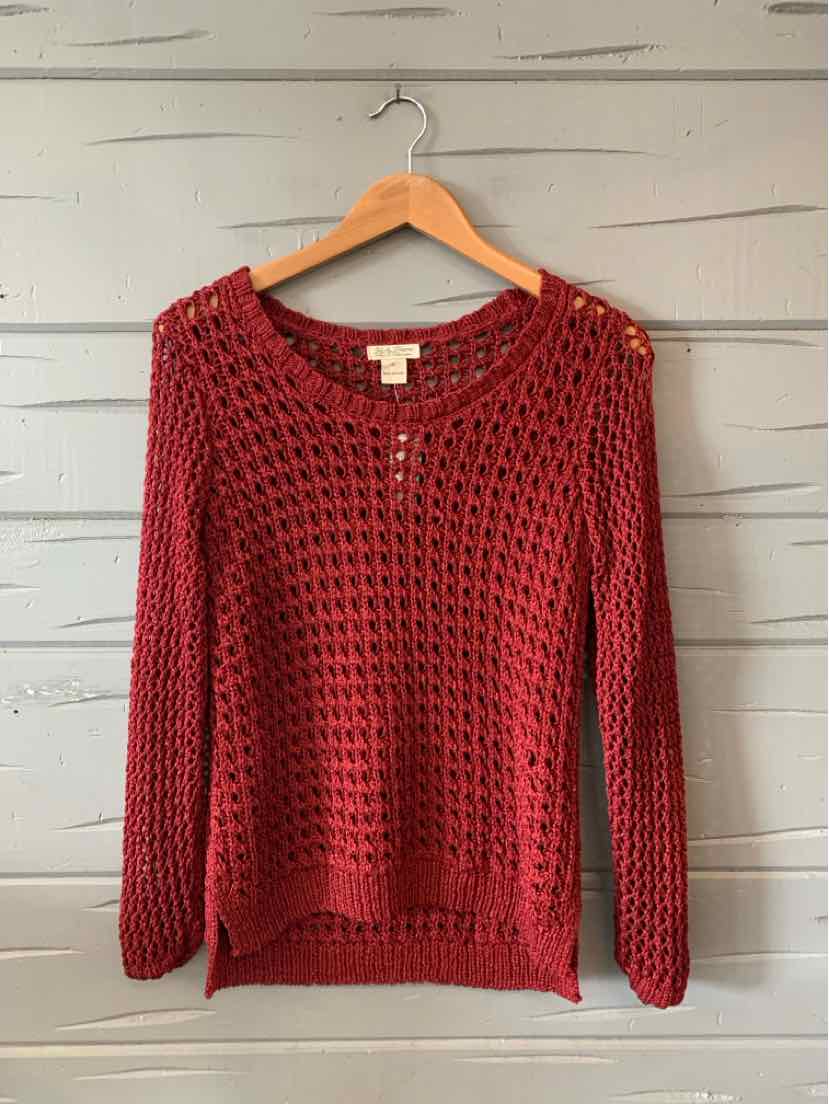 Deep burgundy open-knit sweater with long sleeves and crew neckline hanging on wooden hanger.
