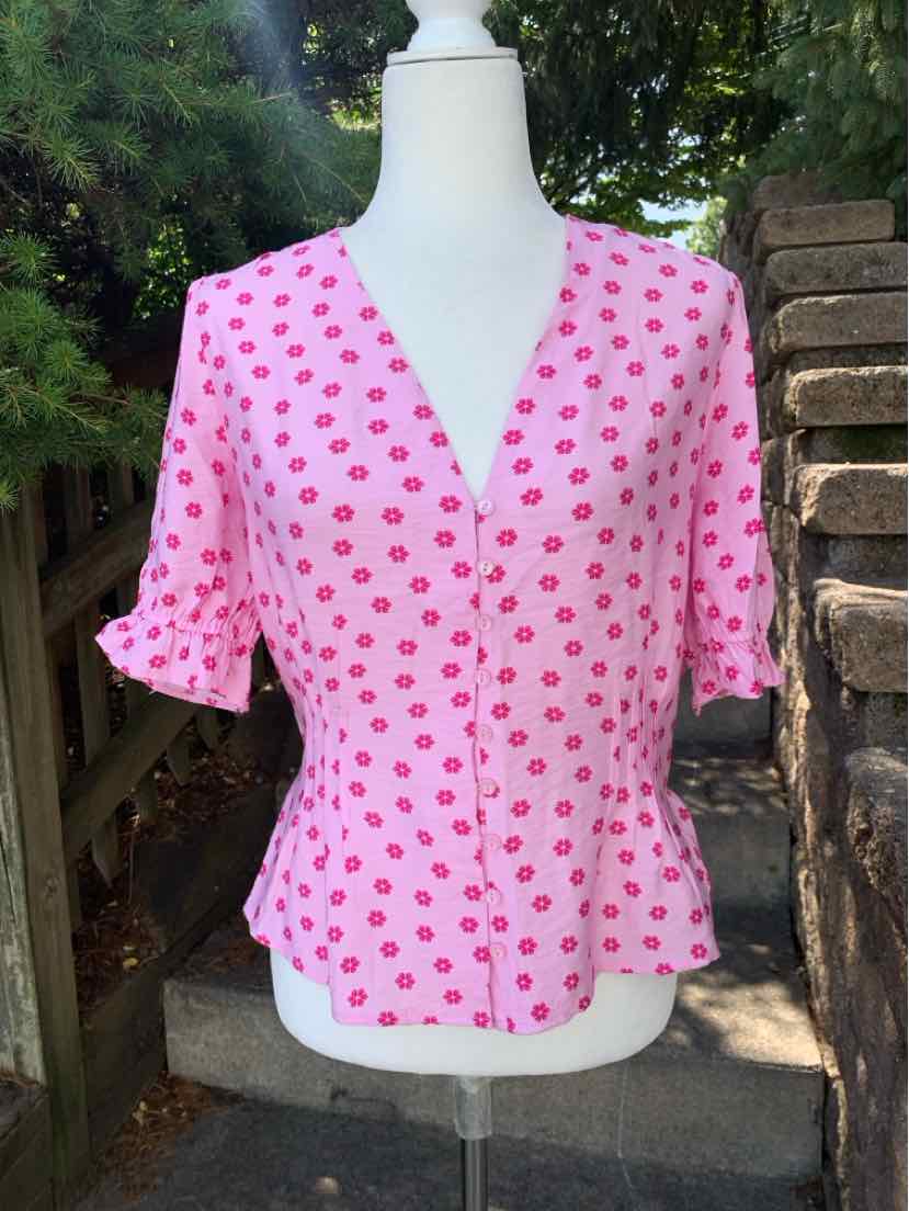 Pink short-sleeve blouse with red polka dots, v-neck, button front, and ruffled hem.