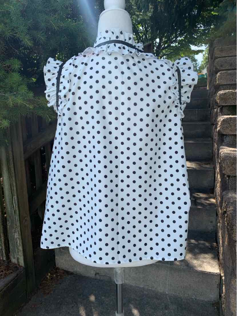 White blouse with black polka dots, short puff sleeves, and a loose fit on a mannequin.