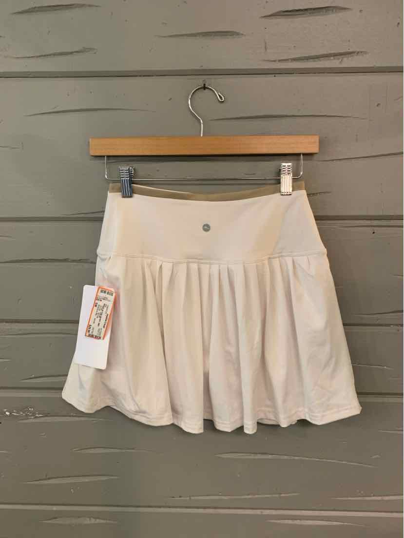 Beige pleated mini skirt with smooth waistband and metal button detail, lightweight fabric.