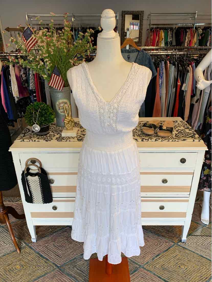 White sleeveless lace dress with V-neck and tiered skirt on mannequin.