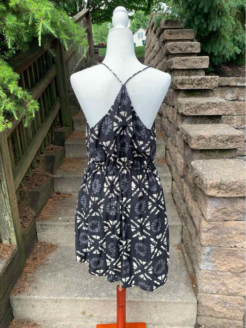 Black sleeveless sundress with white geometric pattern, crisscross back straps, and cinched waist.