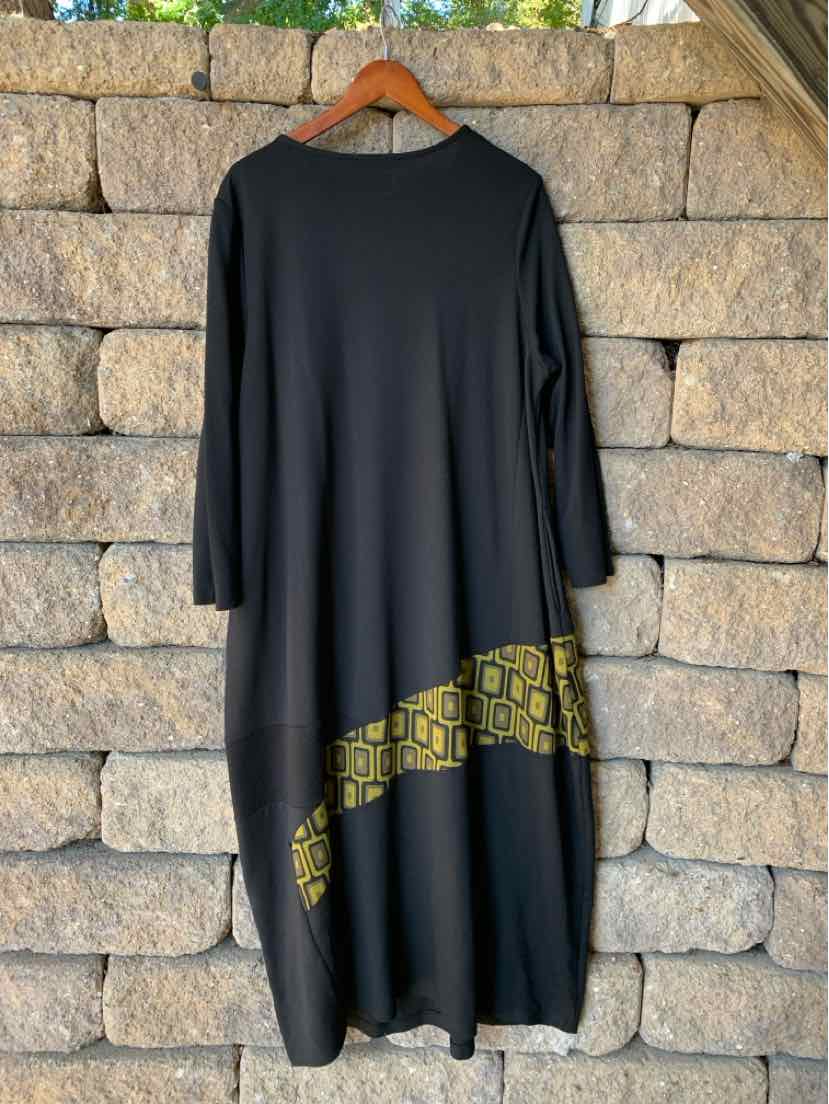 Black Alembika long-sleeve dress with a loose draped silhouette and gold geometric print along the asymmetrical hem.