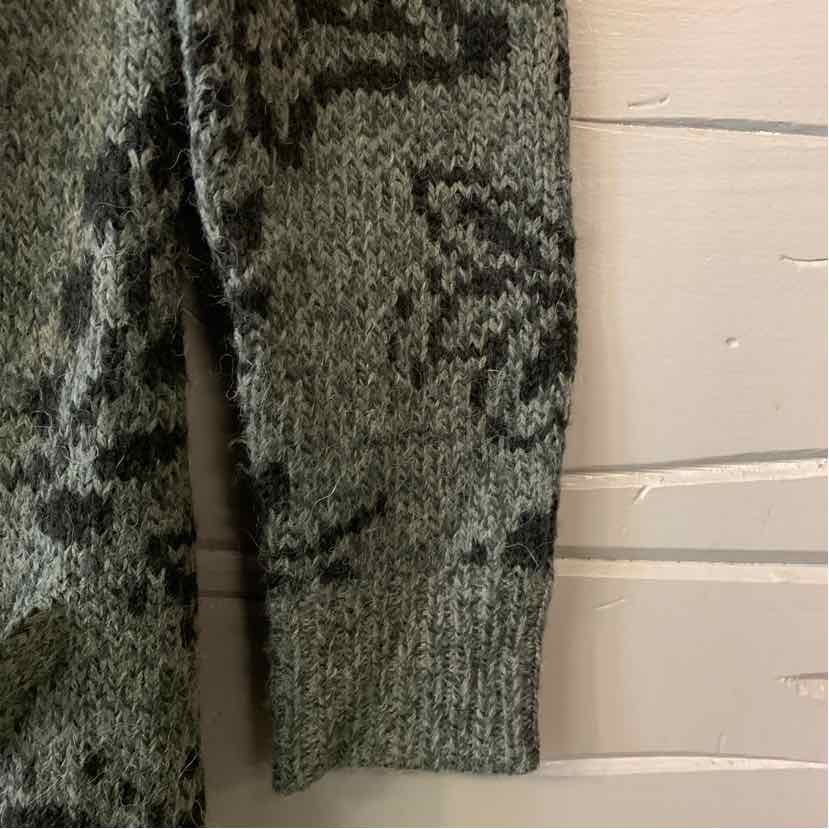 Gray knit sweater sleeve with ribbed cuff and dark abstract pattern.