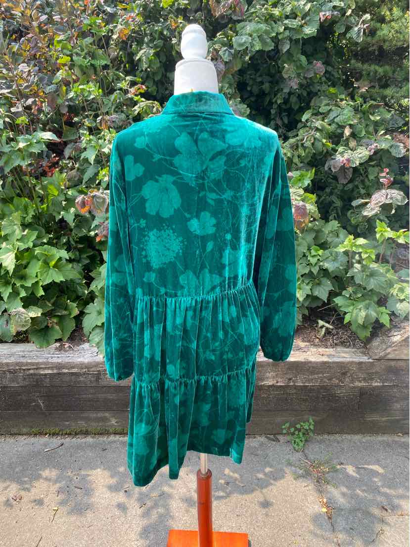 Green floral velvet dress with long sleeves, high collar, and tiered skirt on mannequin outdoors.