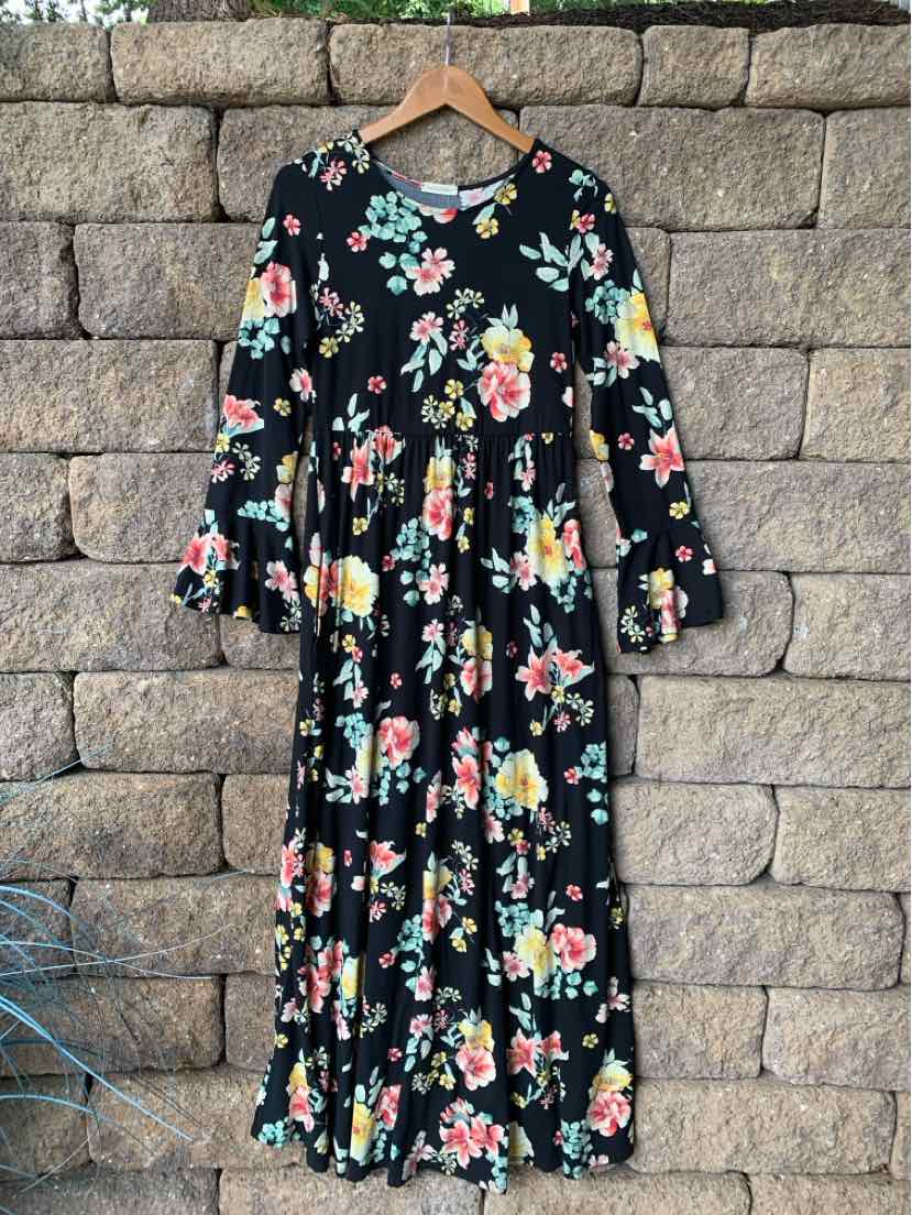 Black cotton midi dress with colorful floral print, ruffled bell sleeves, and relaxed fit.