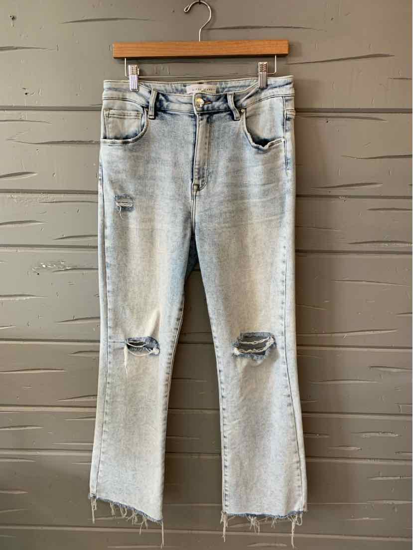 Light wash blue denim jeans with distressed knees and frayed hems, mid-rise fit.