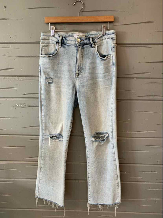 Light wash blue denim jeans with distressed knees and frayed hems, mid-rise fit.