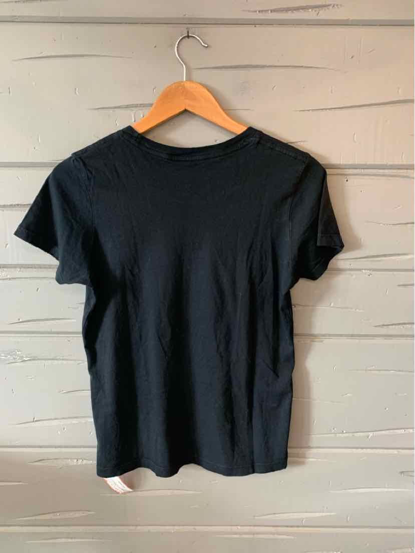 Black short-sleeve crew neck t-shirt in small size hanging on wooden hanger against gray wooden wall.