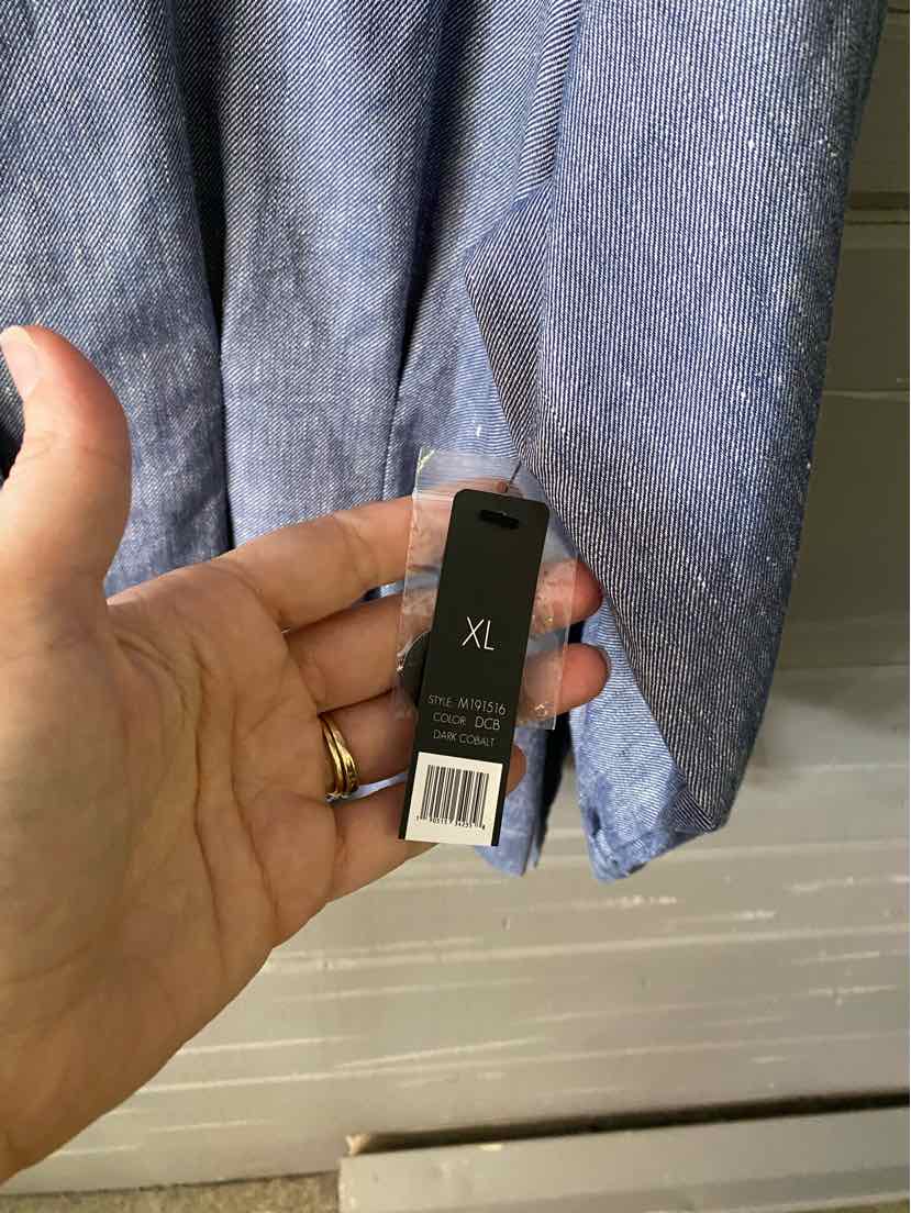 Blue linen blend blouse sleeve with XL size tag held by hand.