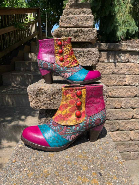 Colorful patchwork ankle boots with pink, turquoise, yellow, and floral patterns, featuring red buttons and a low block heel.