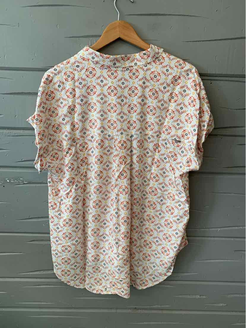White blouse with blue and pink floral print, short sleeves, rounded hem, and relaxed fit in size XL.