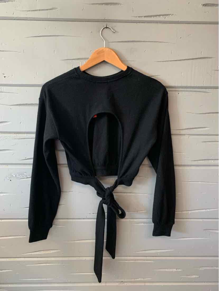 Black long-sleeve cropped top with open back and tie waist detail on wooden hanger.