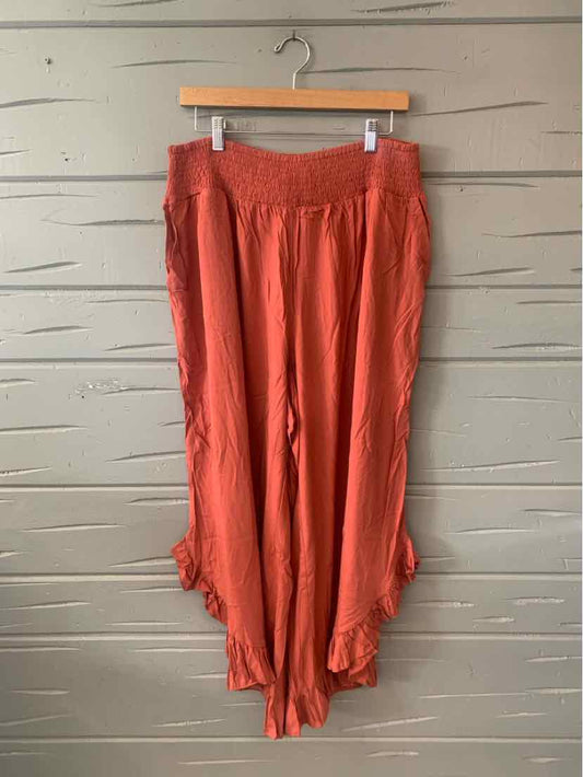 Rust-orange wide-leg pants with smocked elastic waistband and ruffled hems.